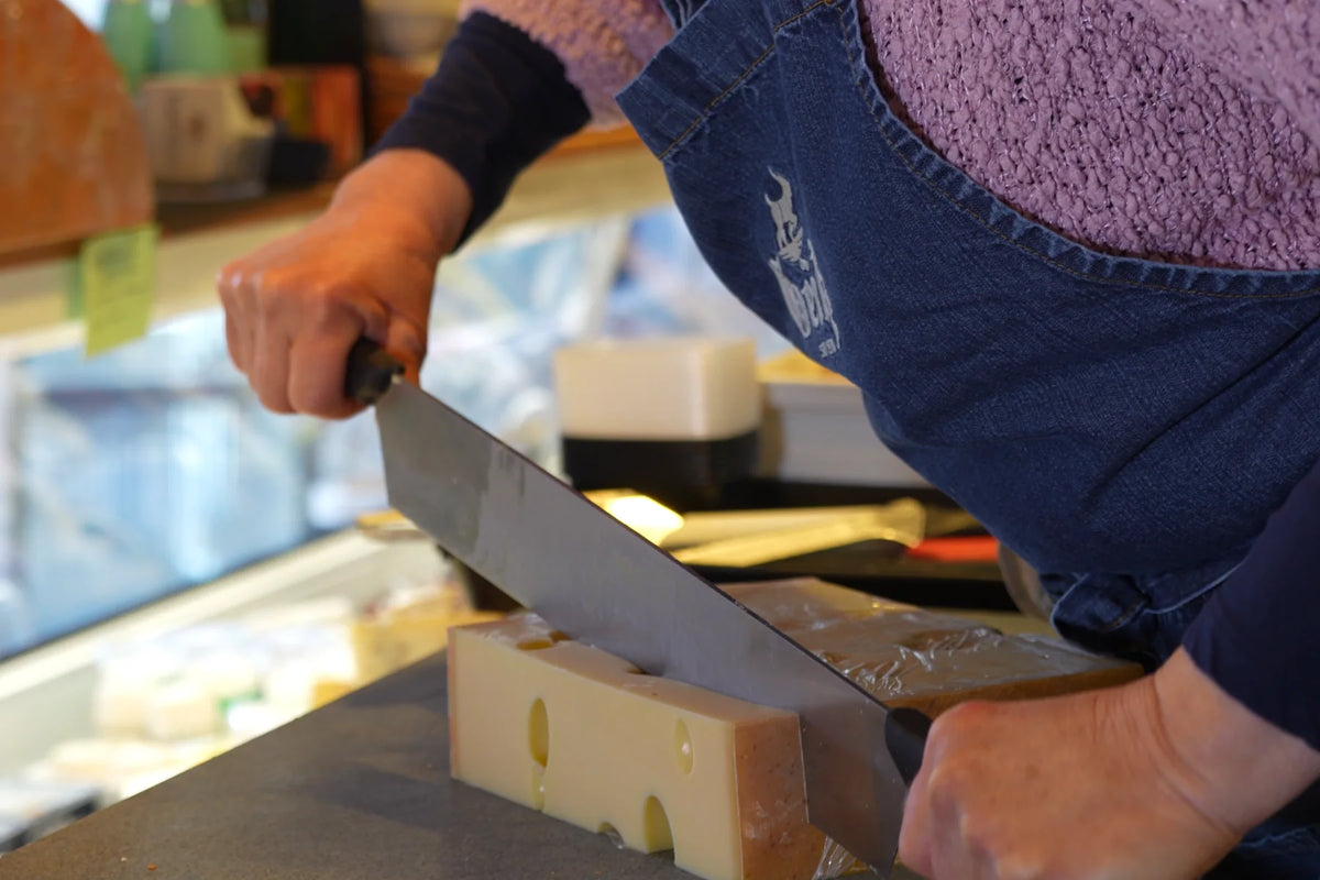 Emmentaler wird am Marktstand mit dem Käsemesser abgeteilt