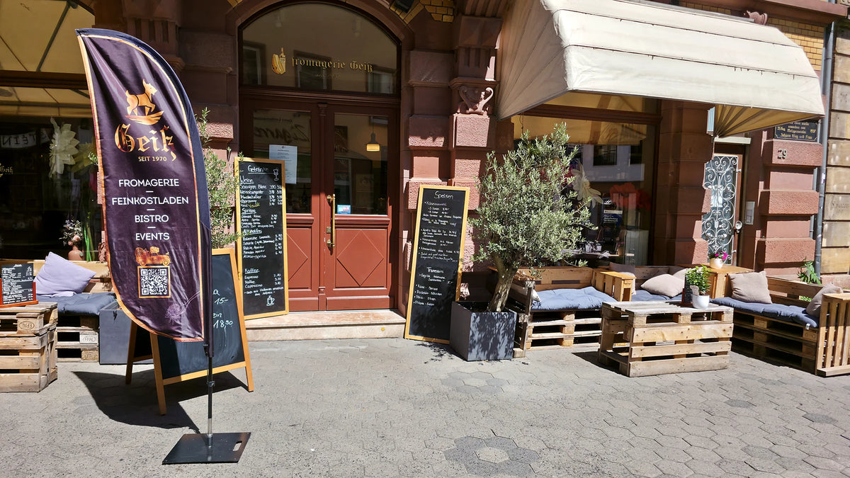 Eingang der Fromagerie Geiß in der Sandgasse mit Banner Fromagerie · Feinkostladen · Bistro · Events