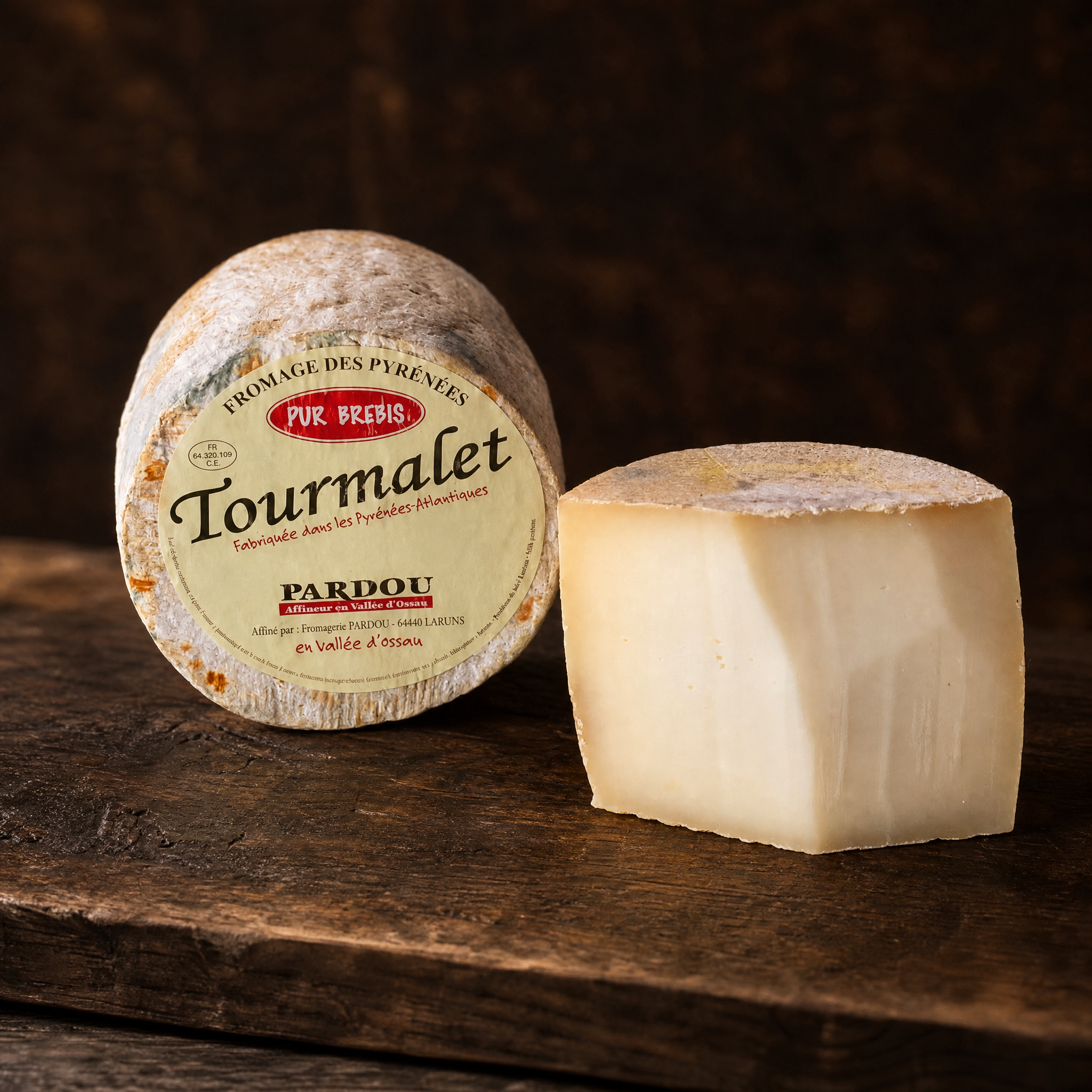 Tourmalet – Schafskäse-Tomme mit Pardou-Etikett und Anschnitt auf dunklem Holzbrett