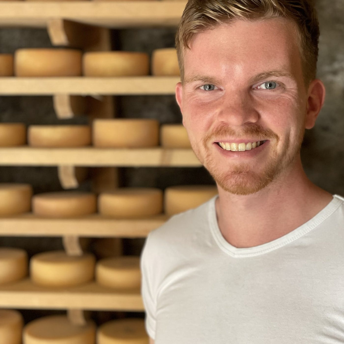 Manuel Geiß im Reifekeller der Fromagerie Geiß vor Regalen mit Käselaiben