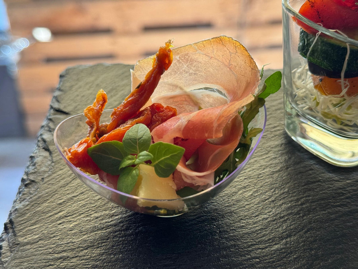Schälchen mit luftgetrocknetem Schinken, getrockneten Tomaten und frischem Oregano