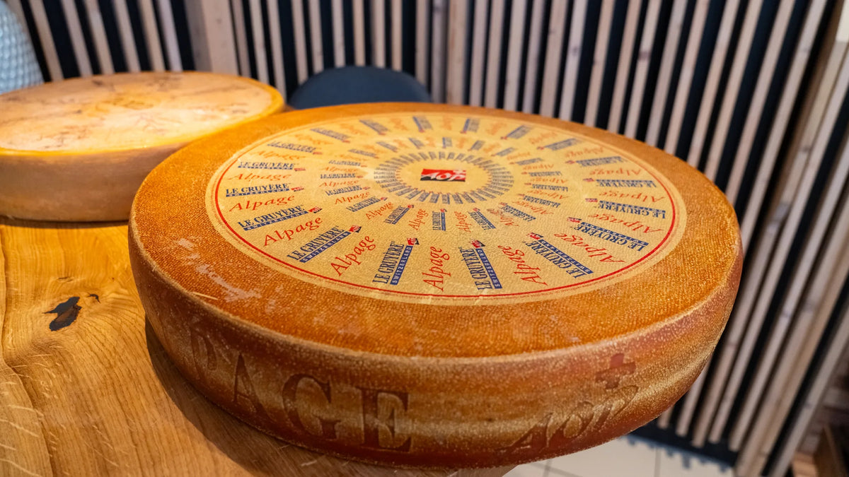 Zwei ganze Laibe Le Gruyère Alpage AOP auf einer Holztheke