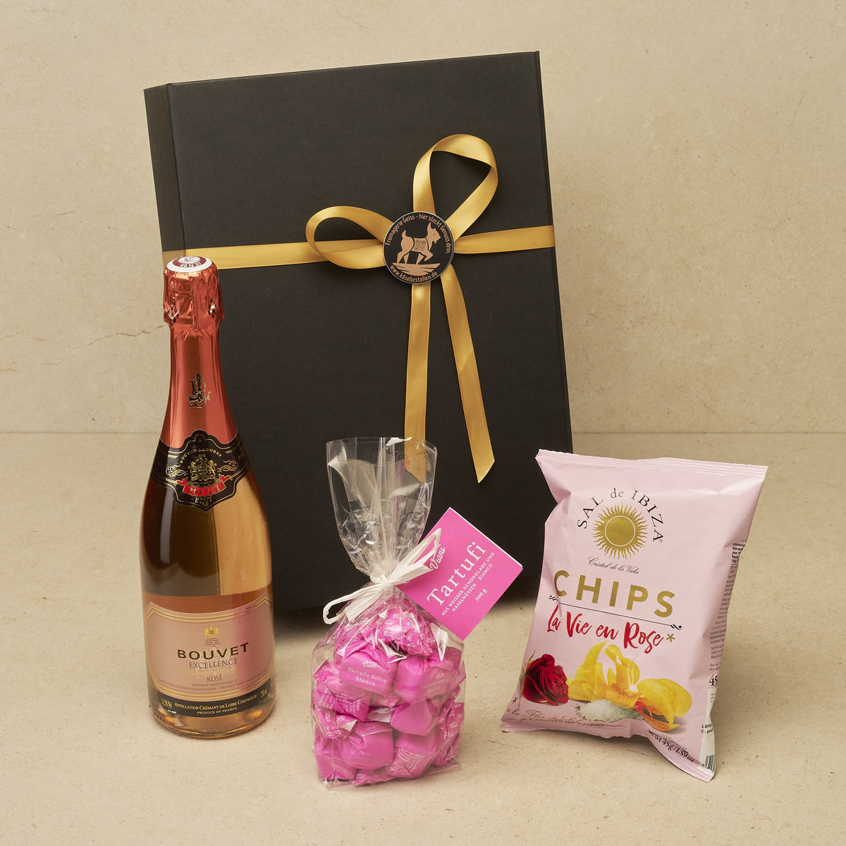Geschenkbox Perlenmoment klein: Bouvet Crémant Rosé, Tartufi Panna Cotta und Chips La Vie en Rose vor der schwarzen Magnetbox