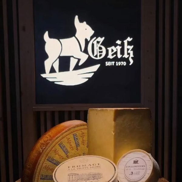 Geiß-Logo-Schild über Käselaiben im Ladengeschäft