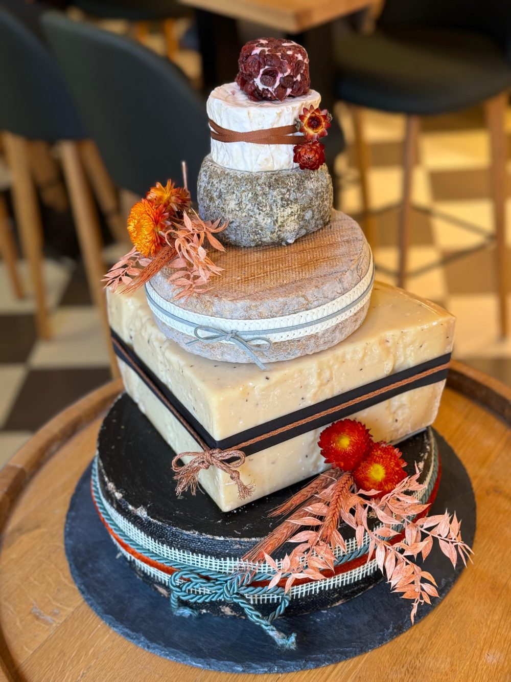 Käsetorte mit einer eckigen Etage mitten im Stapel und orangefarbenen Trockenblumen