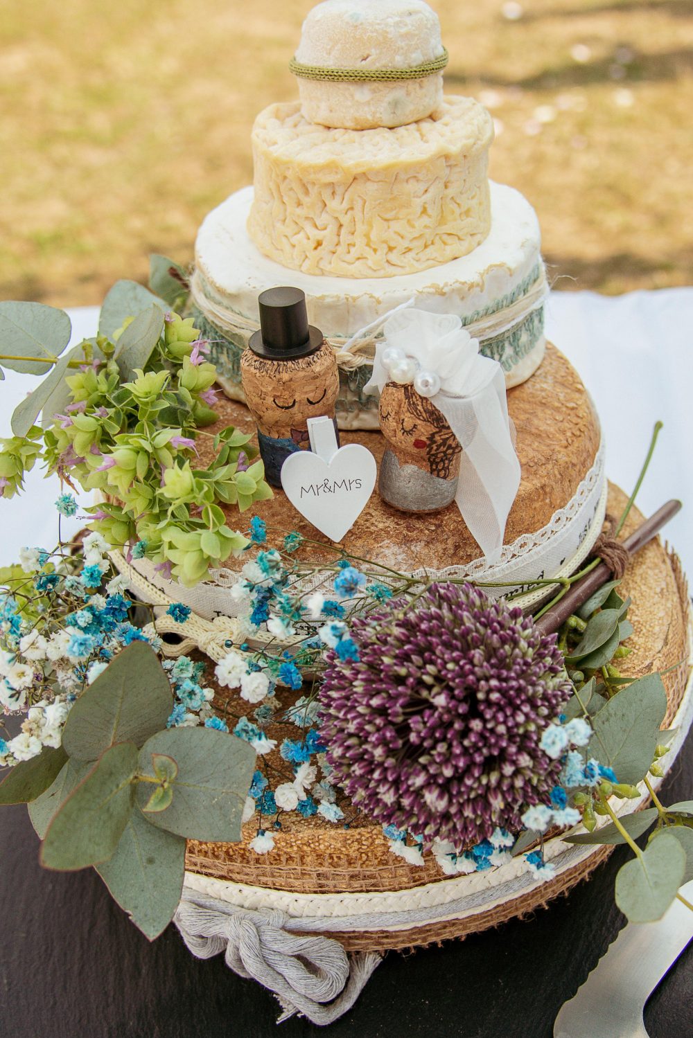 Käsetorte im Freien aufgestellt, mit blauen Trockenblumen, Sommerhochzeit