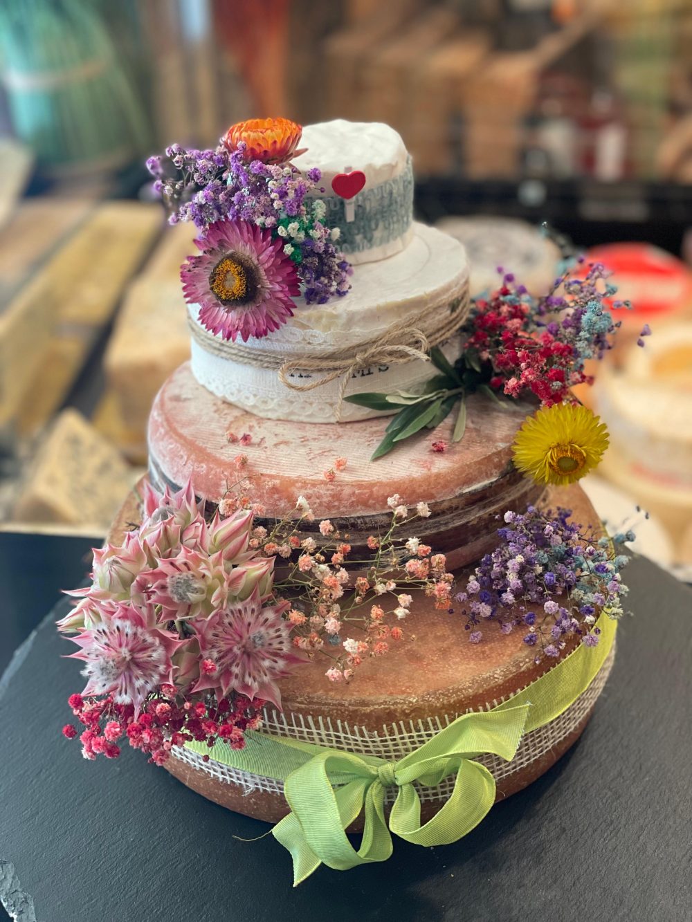 Käsetorte in Lila und Pink mit Sukkulenten und grünem Satinband