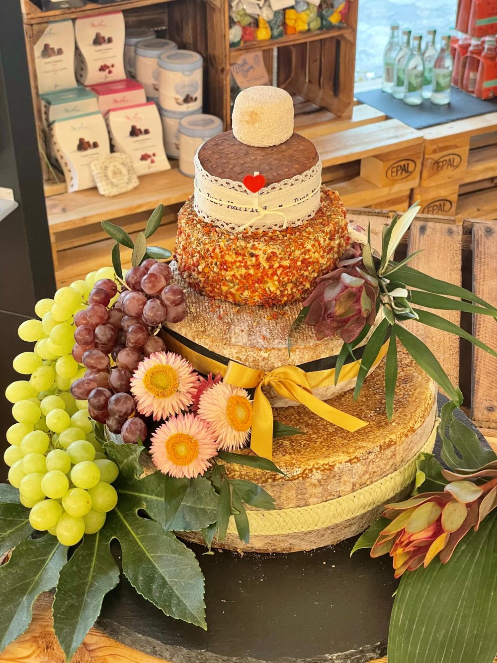 Käsetorte mit gelben Strohblumen, Weintrauben und Feigen als Kranz