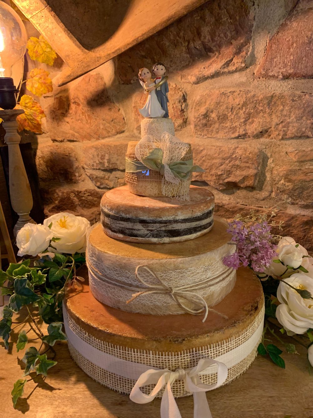 Käsetorte vor einer alten Sandsteinwand mit Trockenblumen in Altrosa