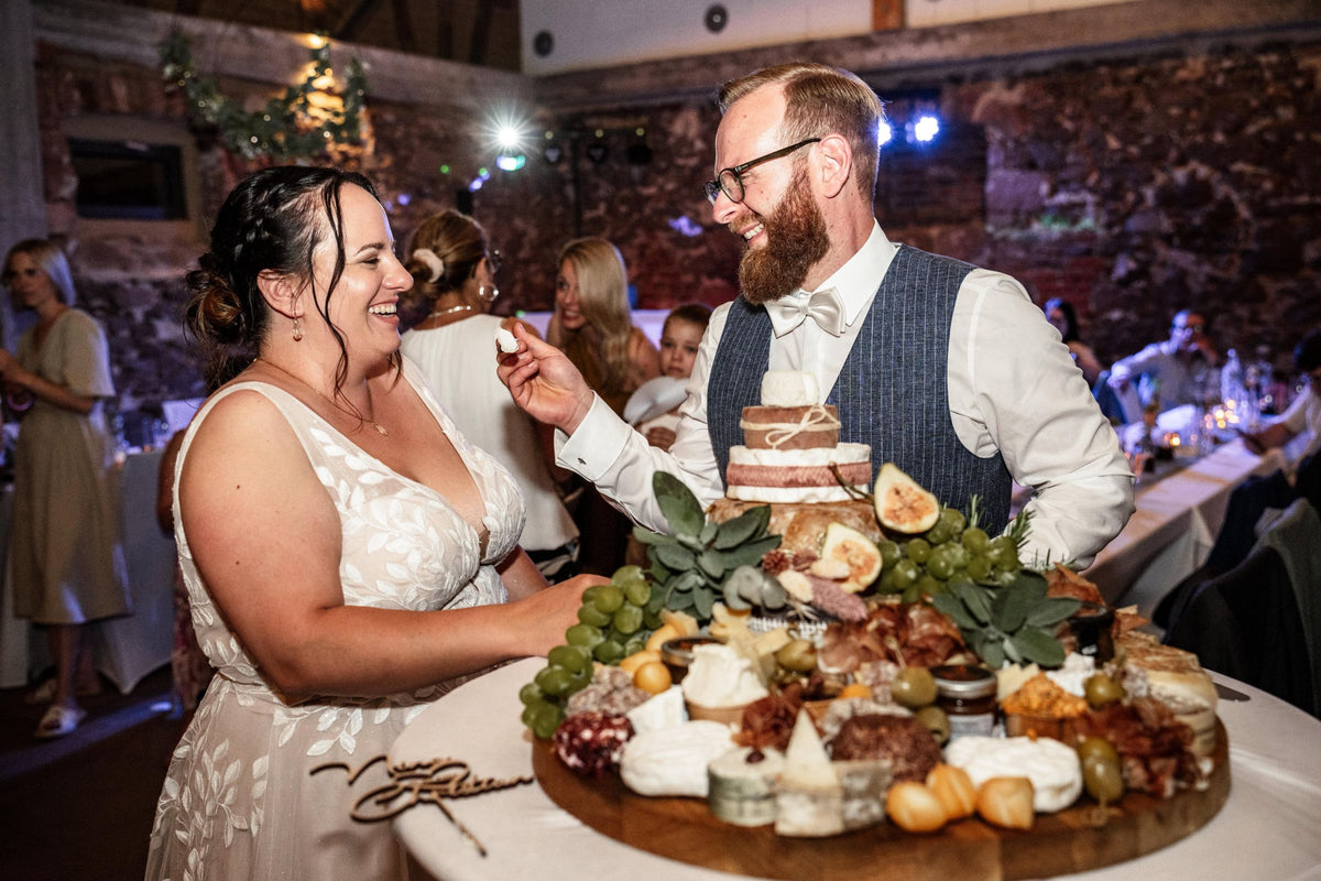 Brautpaar beim Anschnitt einer Käse-Hochzeitstorte auf einer großen Käseplatte