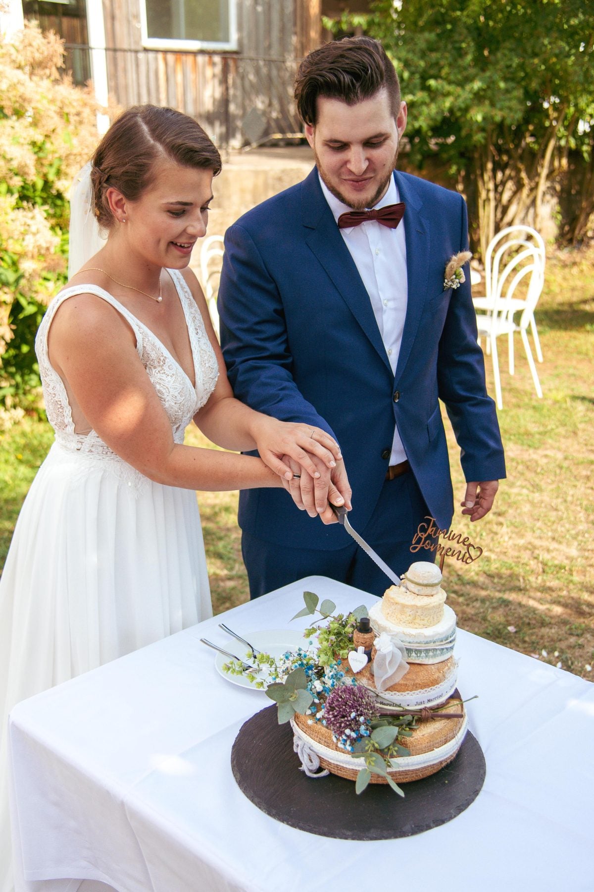 Brautpaar schneidet bei einer Sommerhochzeit im Freien eine Käsetorte an
