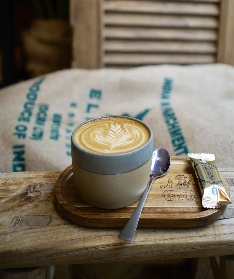 Cappuccino auf einem Holzbrett mit dem Schriftzug Le Petit Geiß
