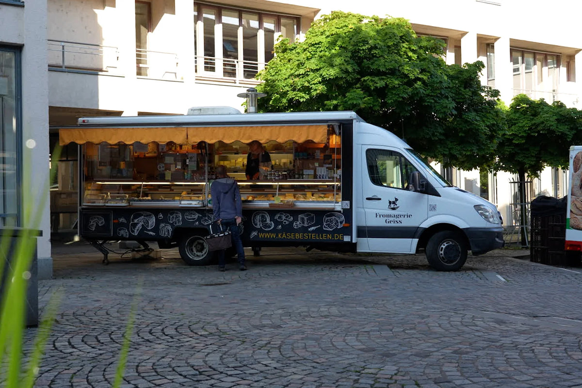 Der Marktwagen auf dem Platz, ein Kunde steht an der Theke