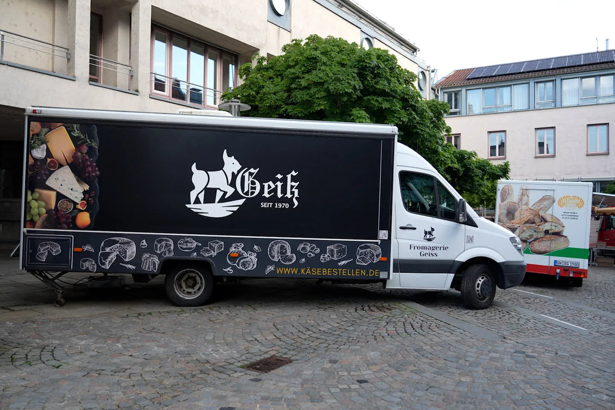 Seitenansicht des Geiß-Marktwagens mit Logo und der Adresse kaesebestellen.de