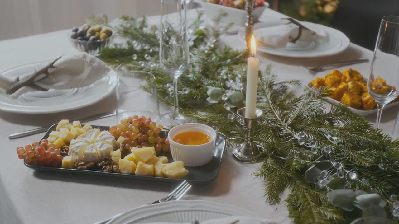 Weihnachtlich gedeckte Tafel mit Käseplatte, Kerze und Tannengrün