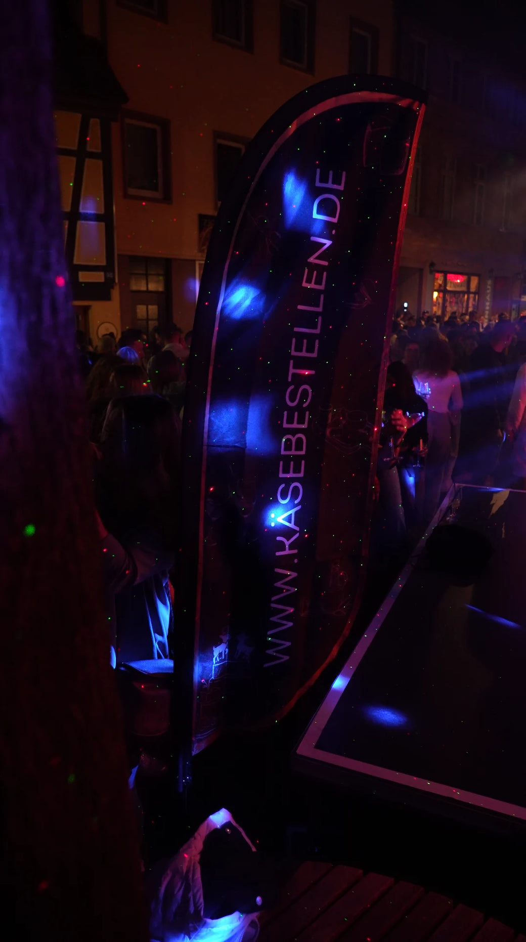 Abendstimmung an der Sandgasse — das Käsebestellen-Banner im Licht.
