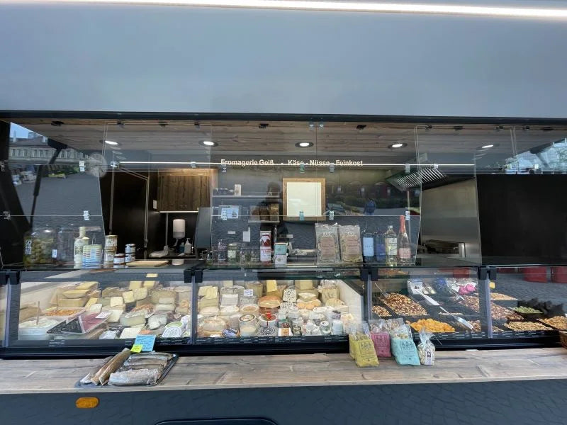 Blick in die Käse- und Feinkosttheke im Marktstand der Fromagerie Geiß, verschiedene Käsesorten und Spezialitäten ausgestellt