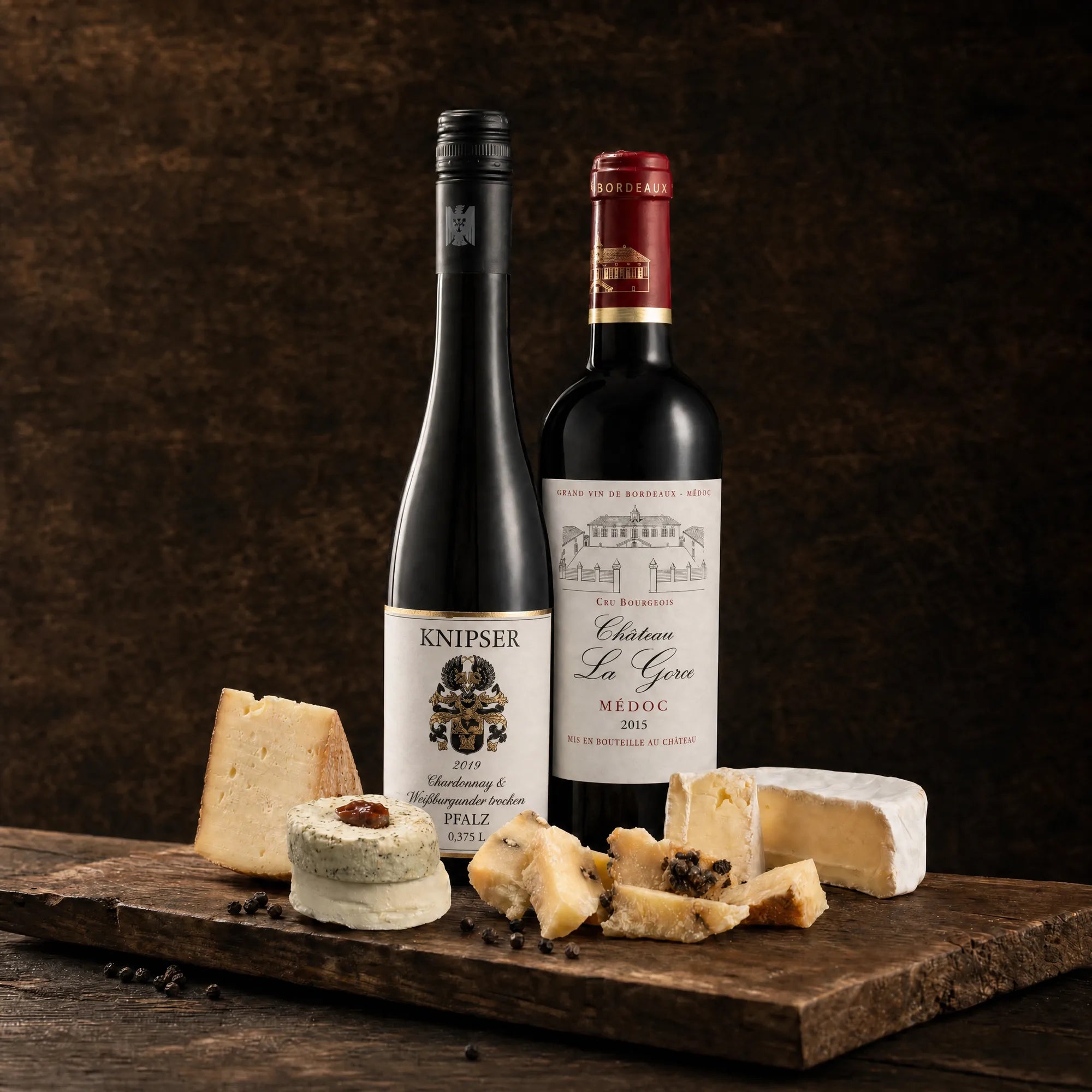 Tasting-Box Duo Bicolor: Weißwein Knipser Chardonnay & Weißburgunder und Rotwein Château La Gorce Médoc mit Käseauswahl auf rustikalem Holzbrett