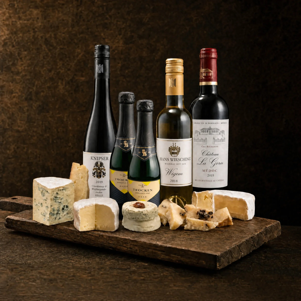 Tasting-Box Sélection Prestige für 4 Personen: Weißwein, zwei Jahrgangs-Sekt-Piccolos, Dessertwein Hans Wirsching Wiqem und Rotwein Médoc mit Käseauswahl samt Blauschimmelkäse auf rustikalem Holzbrett