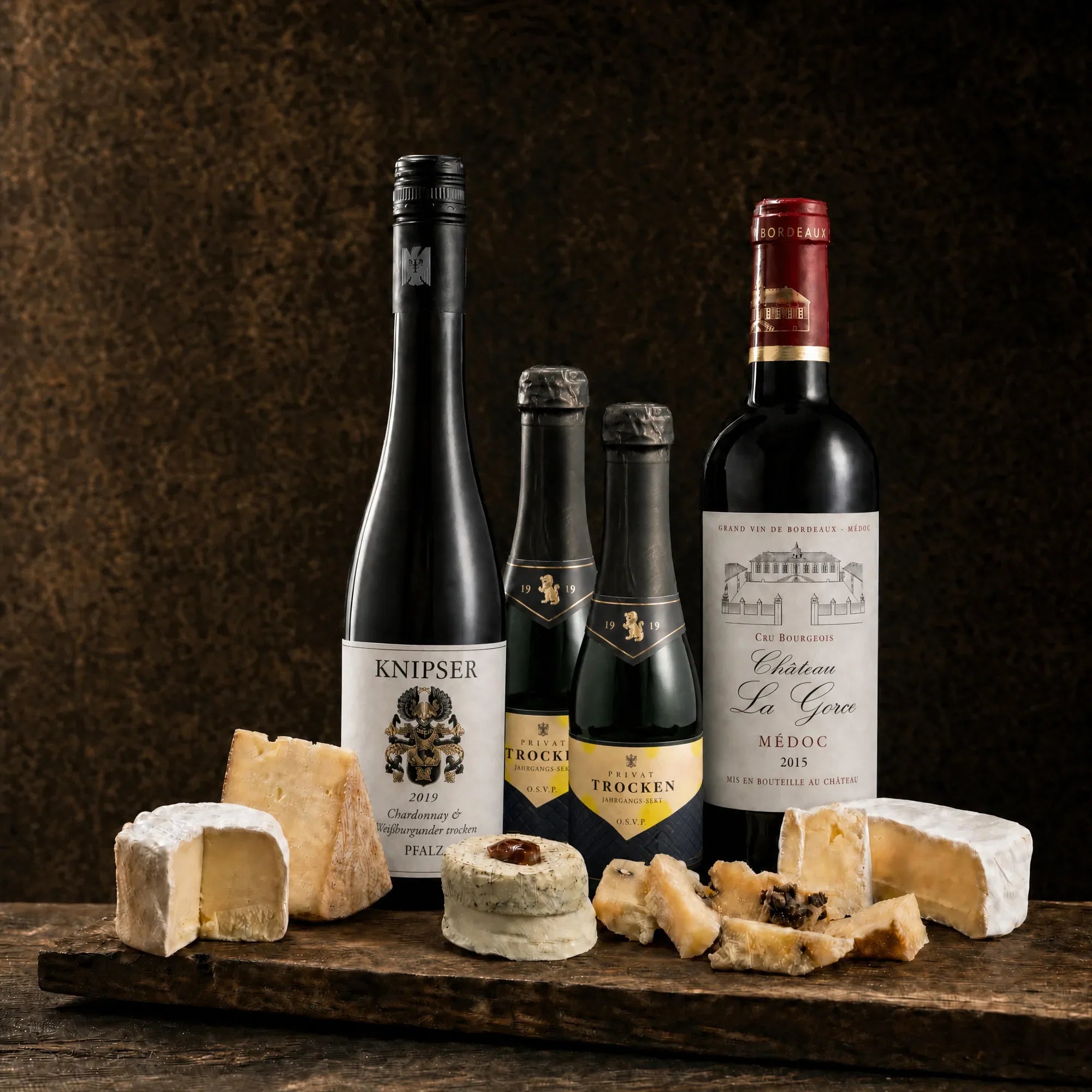 Tasting-Box Trio Royal für 4 Personen: Weißwein, zwei Jahrgangs-Sekt-Piccolos und Rotwein Château La Gorce Médoc mit Käseauswahl auf rustikalem Holzbrett